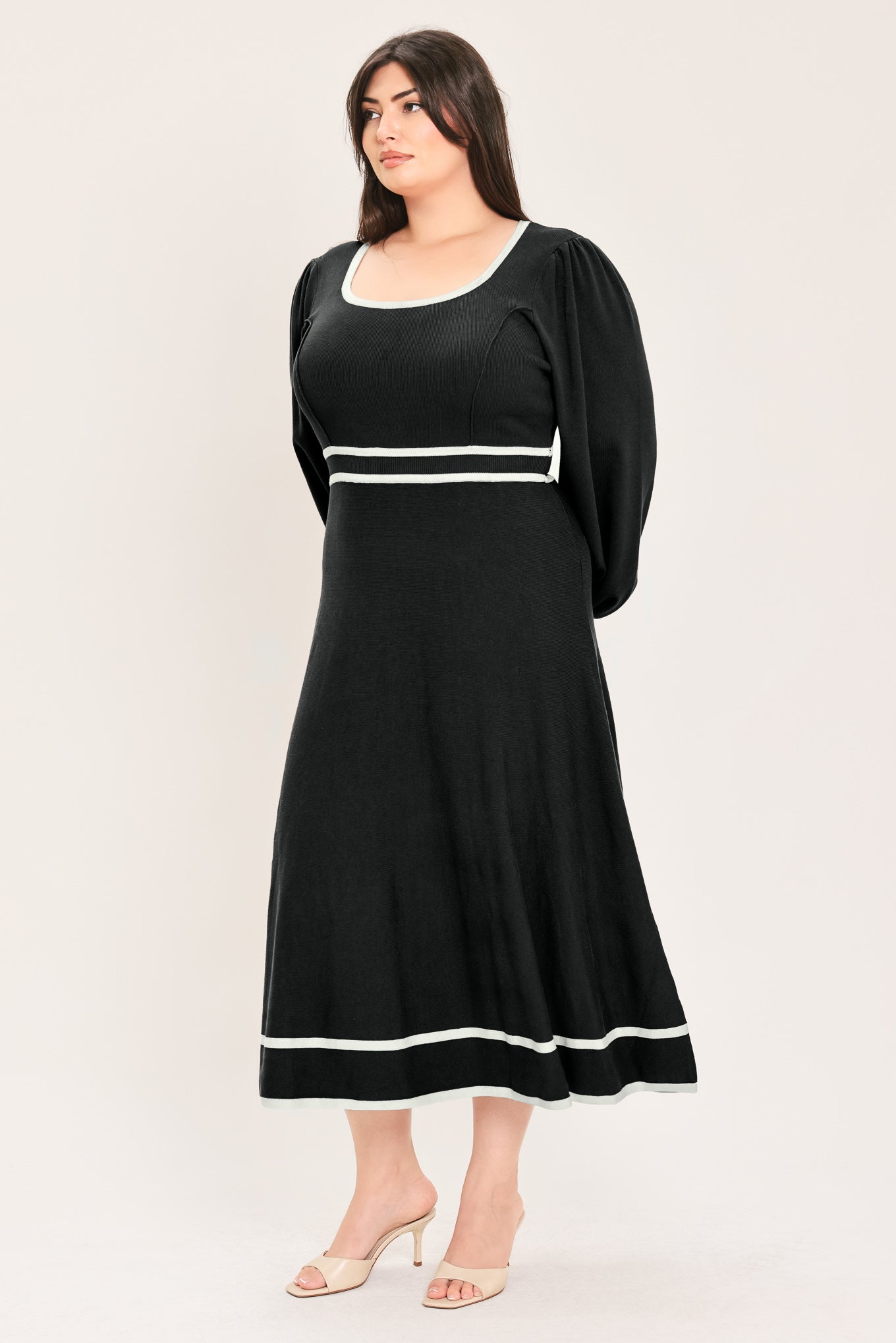 A woman modeling a black midi dress with white trim details, including a scoop neckline, double-breasted waist, and hem | Flying Tomato Curve