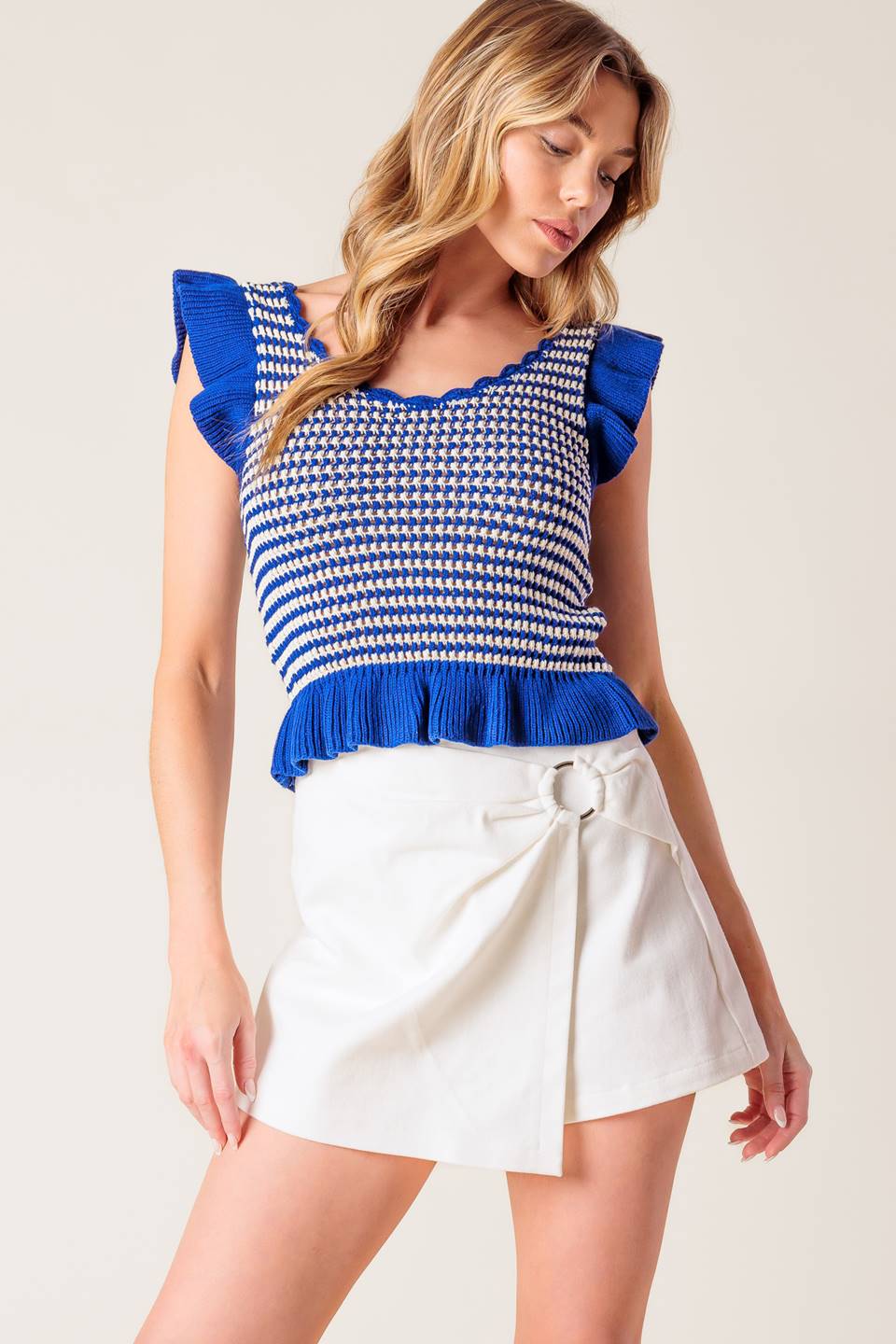 A blue and ivory sweater knit top featuring U neckline, ruffled short sleeve and hemline.