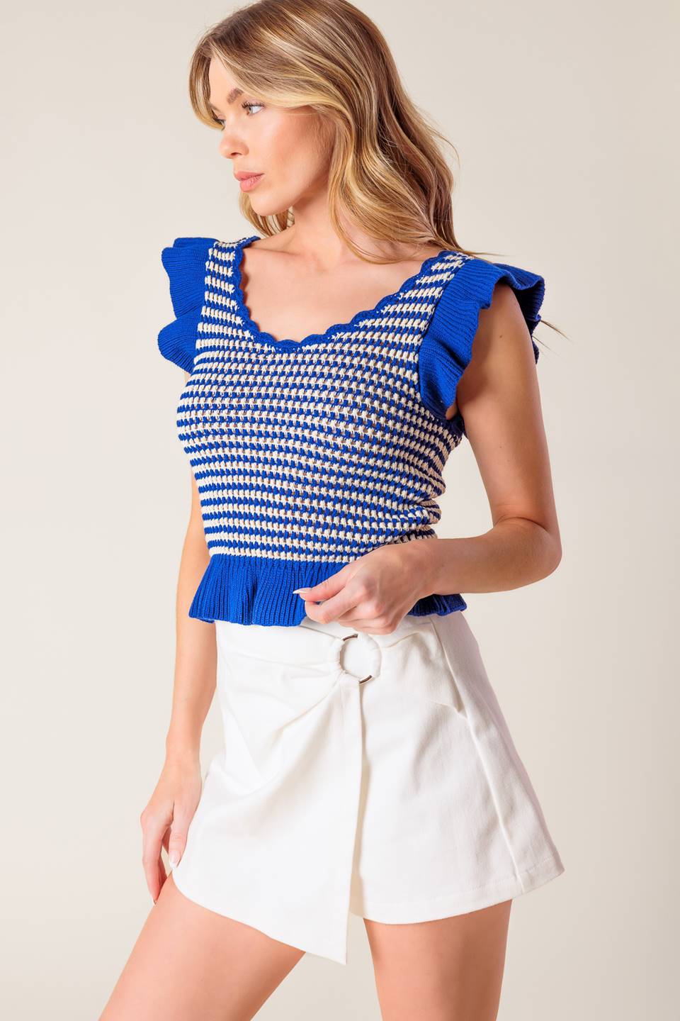 A blue and ivory sweater knit top featuring U neckline, ruffled short sleeve and hemline.