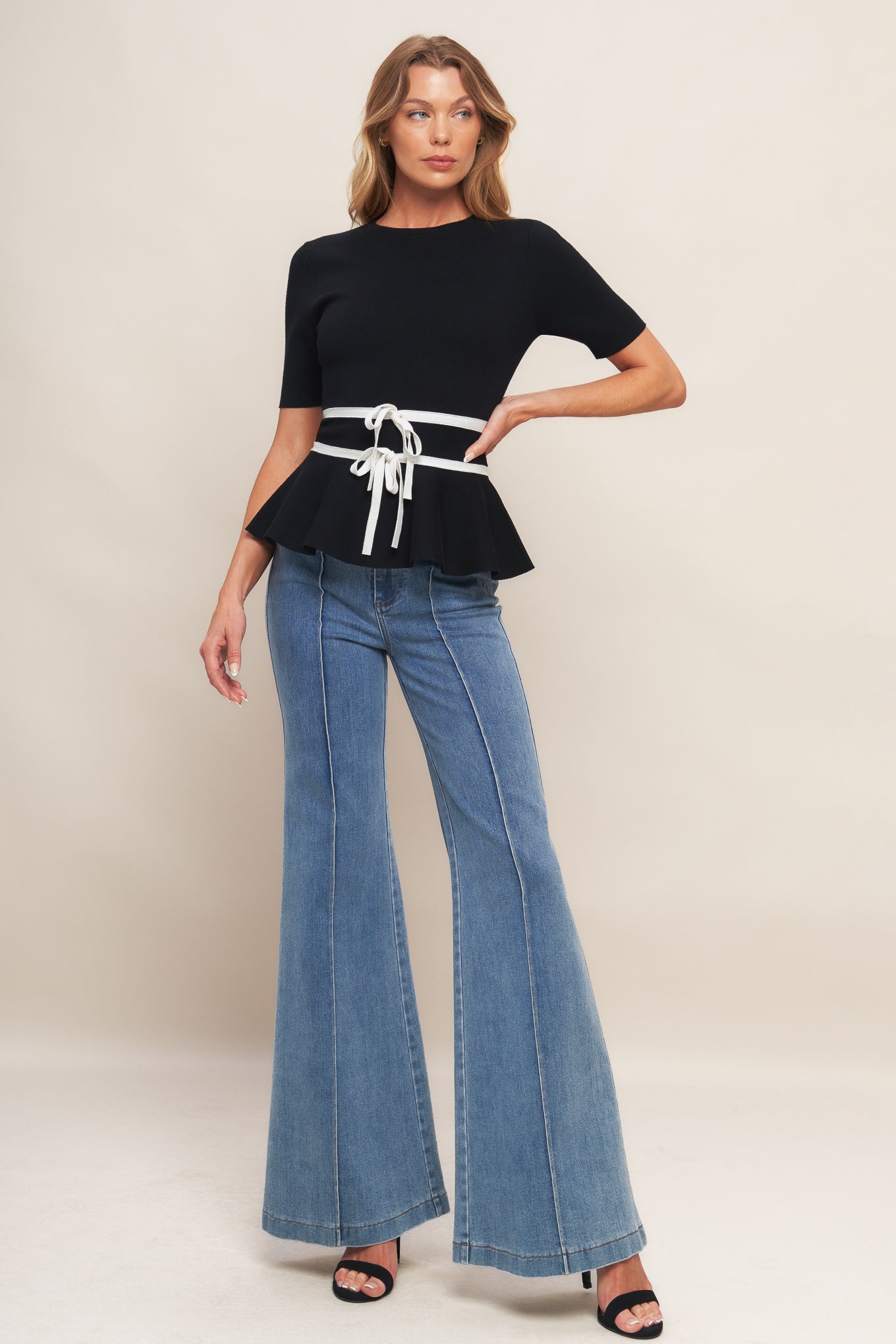 A solid sweater knit top featuring round neckline, short sleeve, bow front, peplum and back zipper closure