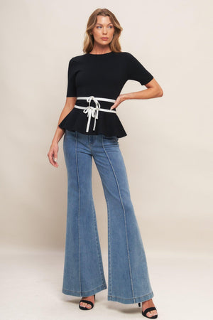 A solid sweater knit top featuring round neckline, short sleeve, bow front, peplum and back zipper closure