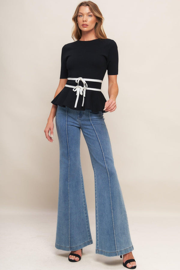 A solid sweater knit top featuring round neckline, short sleeve, bow front, peplum and back zipper closure