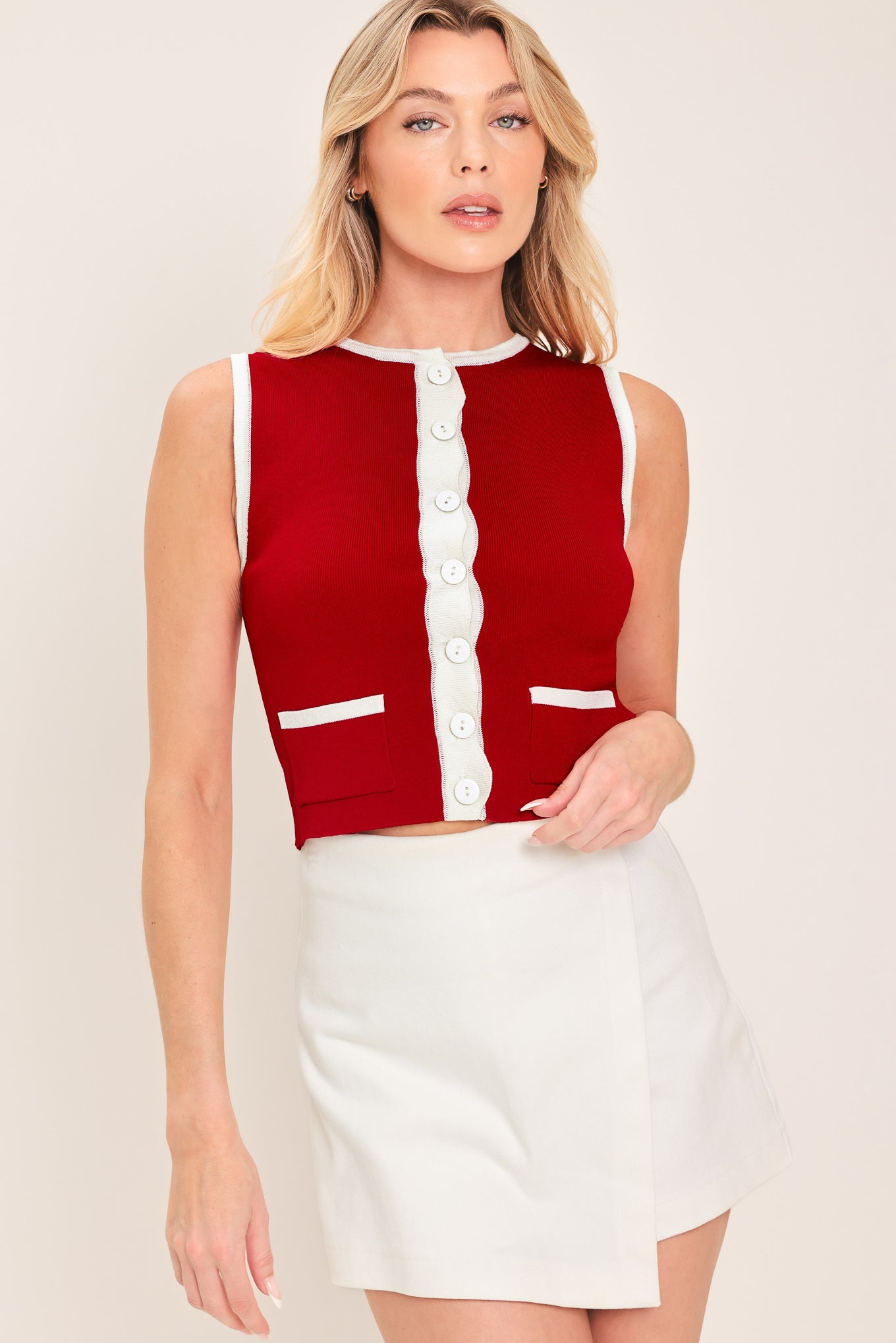 Woman wearing a sleeveless red and white color blocked sweater knit top top with white buttons | Flying Tomato