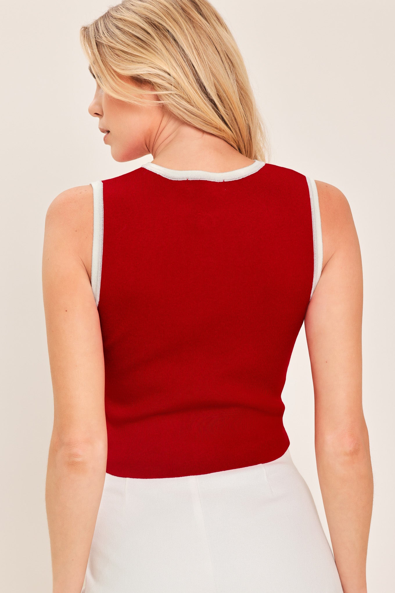 Woman wearing a sleeveless red and white color blocked sweater knit top top with white buttons | Flying Tomato