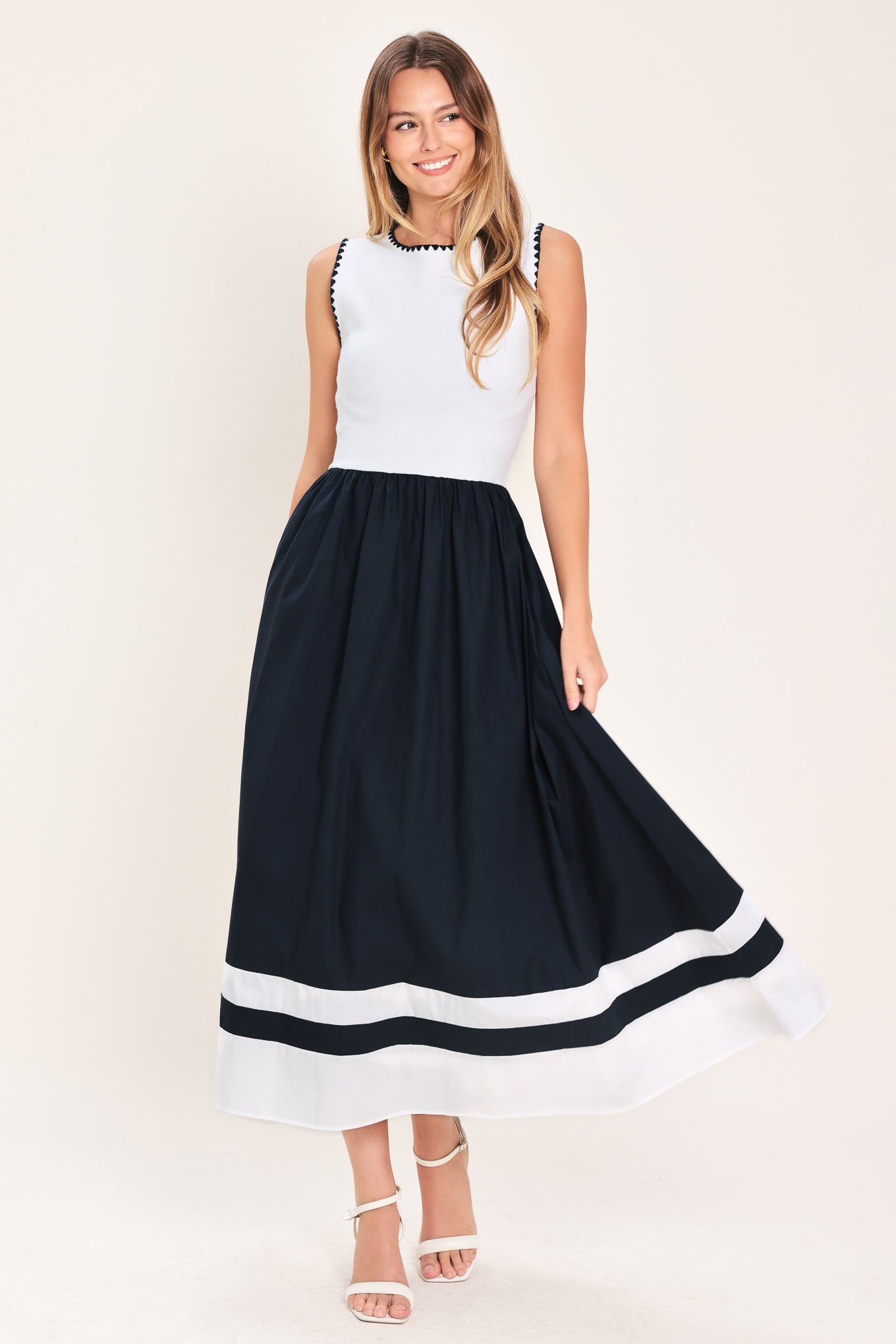 Woman wearing a white and navy blue sweater knit and woven combination midi dress featuring round neckline, sleeveless and full skirt | Flying Tomato