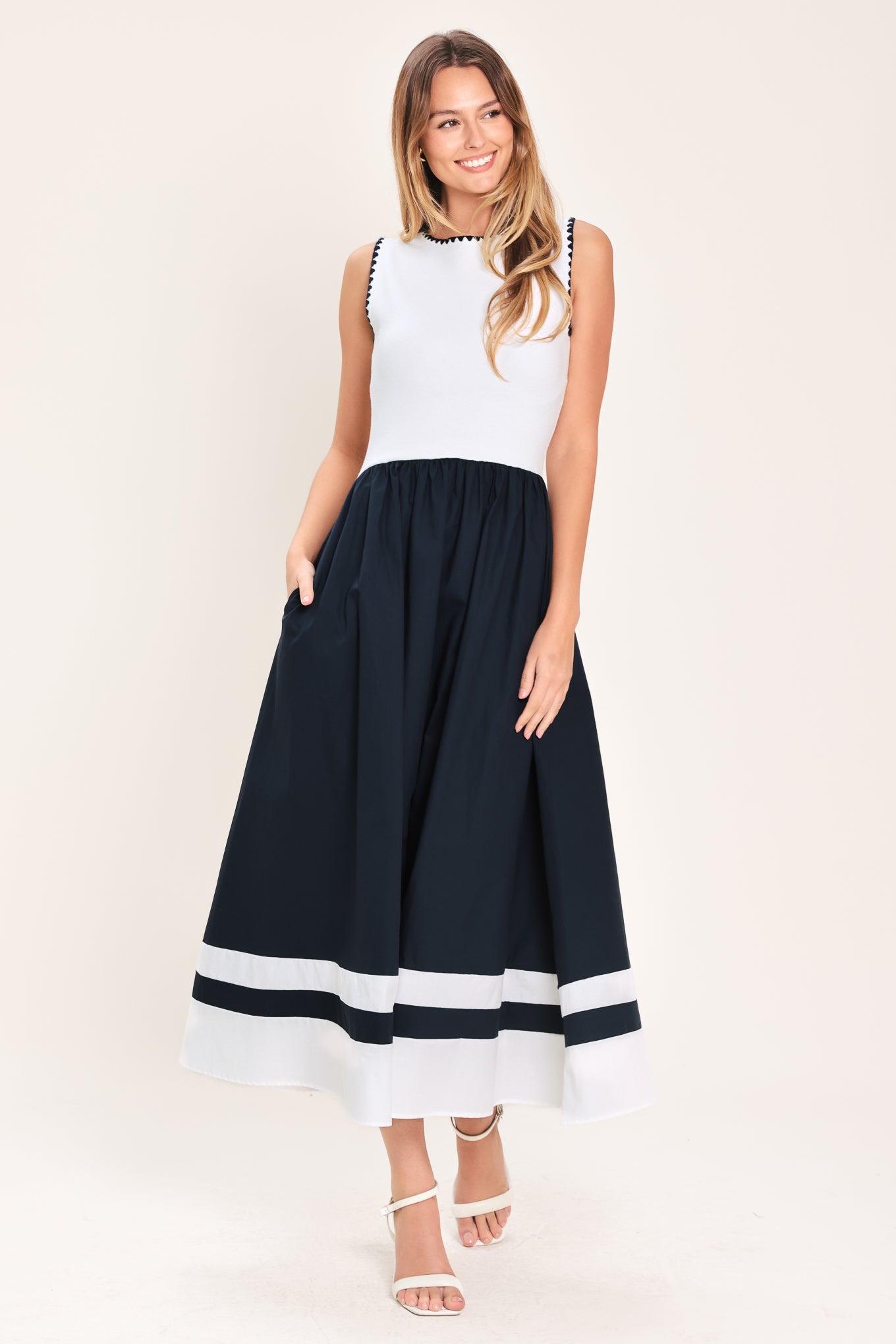 Woman wearing a white and navy blue sweater knit and woven combination midi dress featuring round neckline, sleeveless and full skirt | Flying Tomato