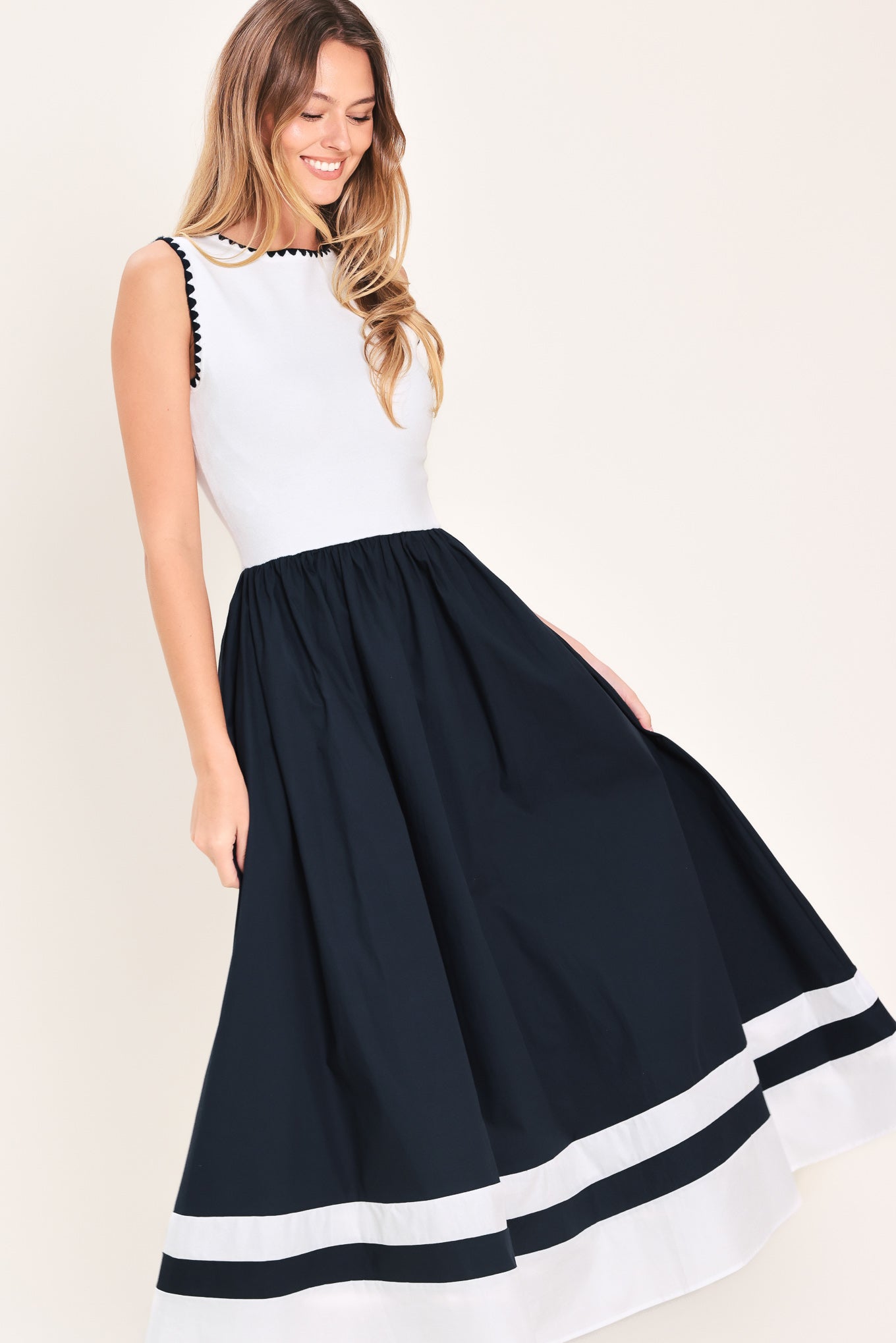 Woman wearing a white and navy blue sweater knit and woven combination midi dress featuring round neckline, sleeveless and full skirt | Flying Tomato