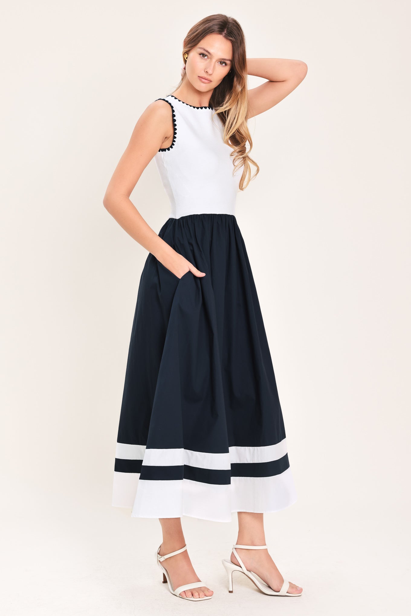 Woman wearing a white and navy blue sweater knit and woven combination midi dress featuring round neckline, sleeveless and full skirt | Flying Tomato