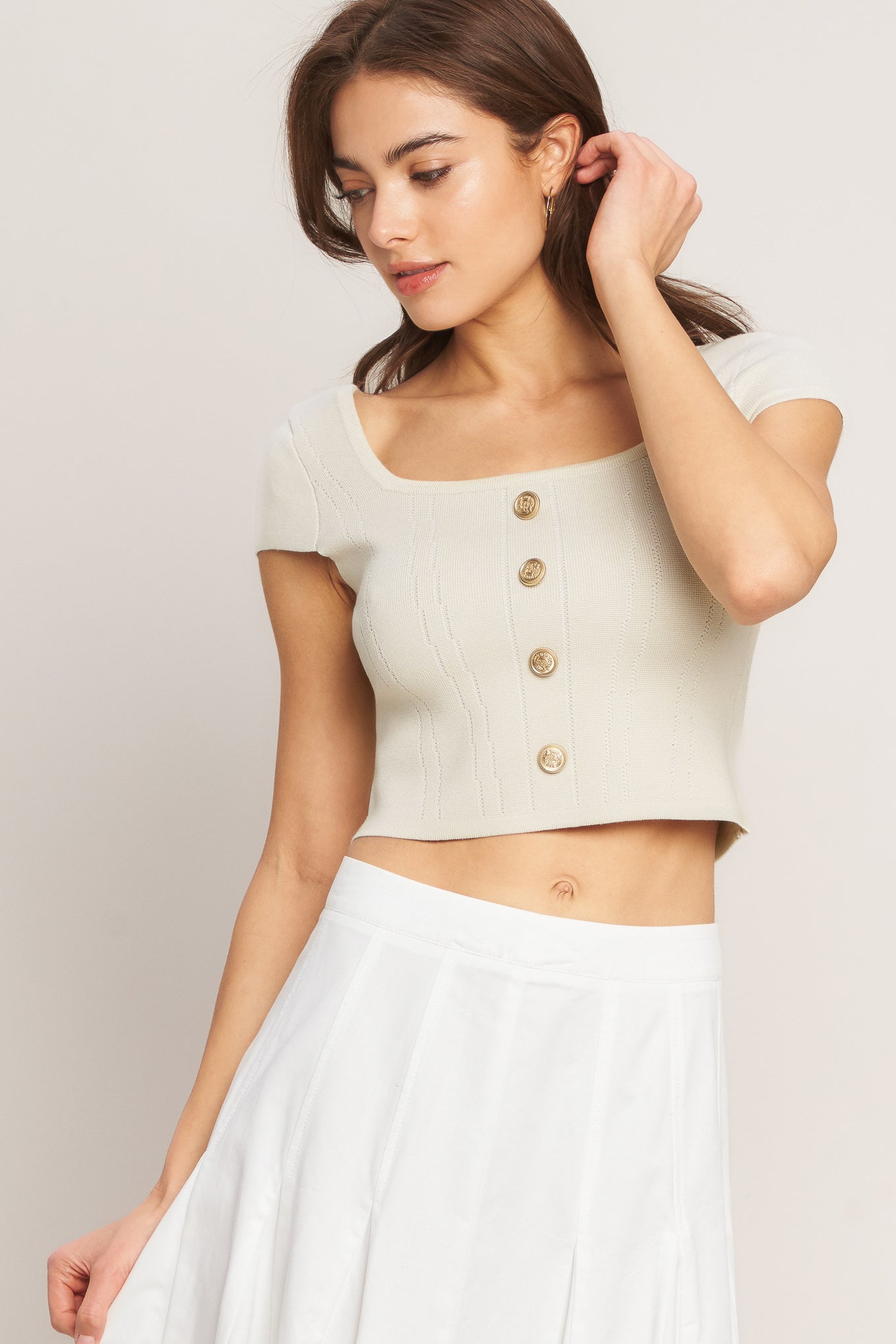 A sweater knit top featuring square neckline, cap sleeve and front button detail