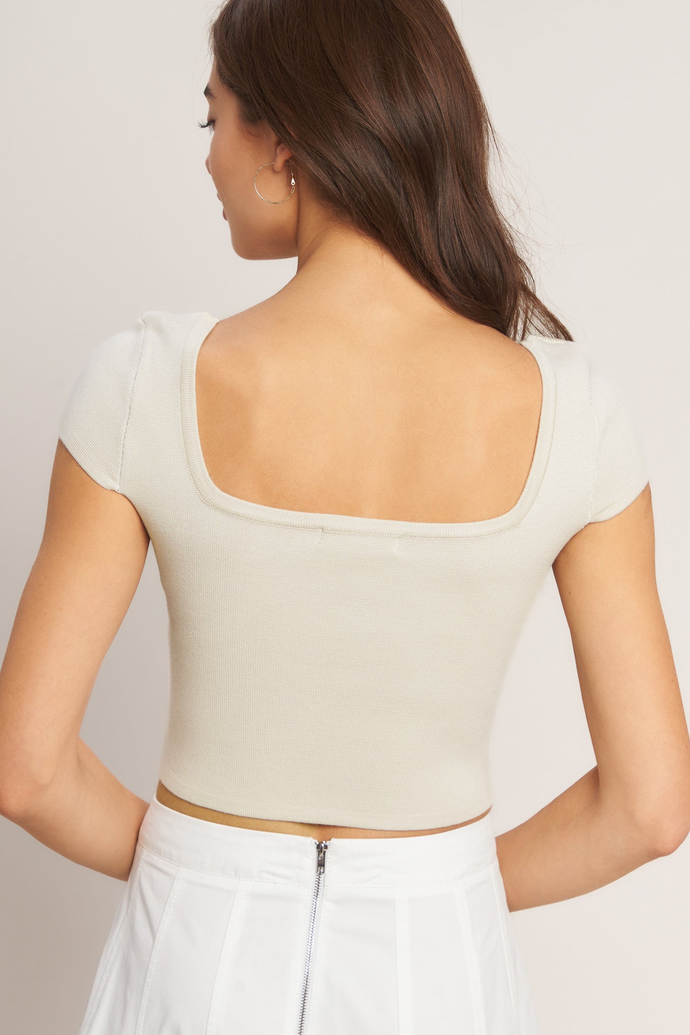 A sweater knit top featuring square neckline, cap sleeve and front button detail