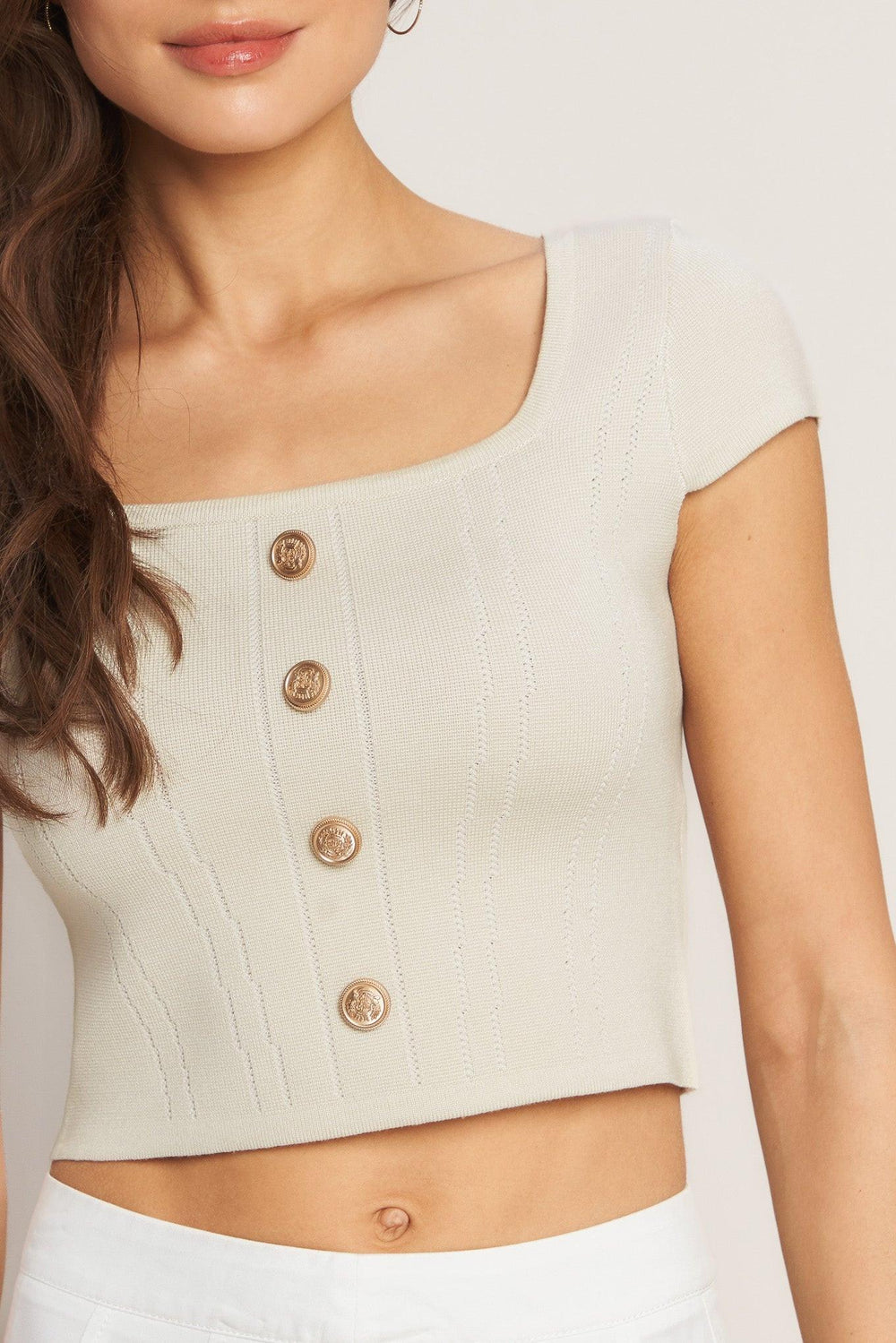 A sweater knit top featuring square neckline, cap sleeve and front button detail