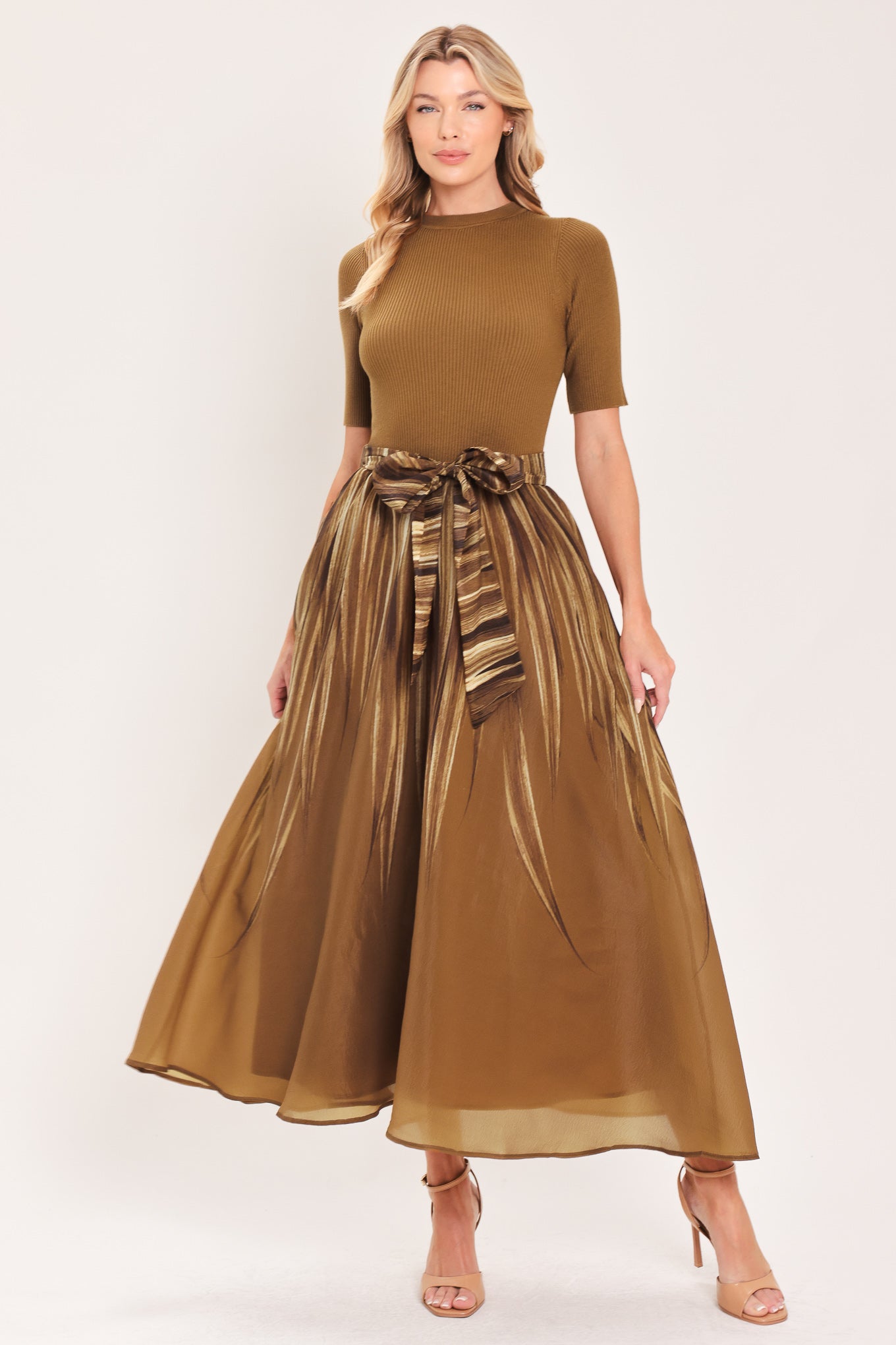 A woman modeling a brown midi dress with a short-sleeve mock neck top, pleated skirt, and a matching fabric tie belt | Flying Tomato
