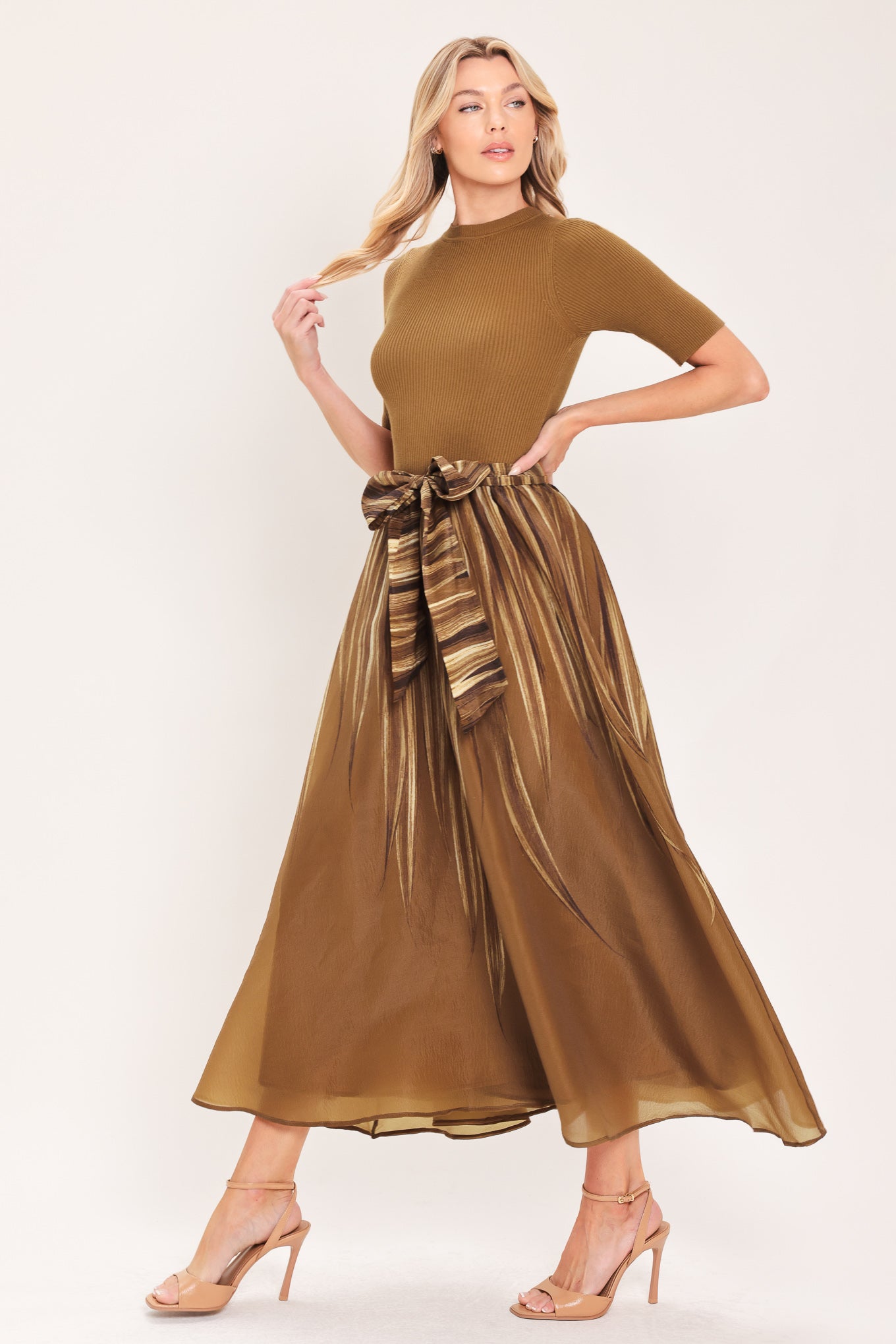 A woman modeling a brown midi dress with a short-sleeve mock neck top, pleated skirt, and a matching fabric tie belt | Flying Tomato