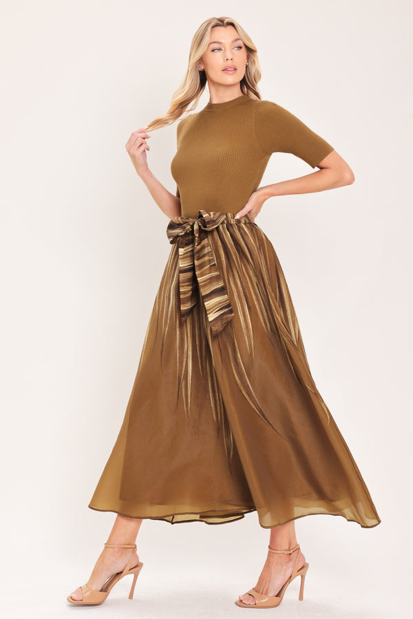 A woman modeling a brown midi dress with a short-sleeve mock neck top, pleated skirt, and a matching fabric tie belt | Flying Tomato