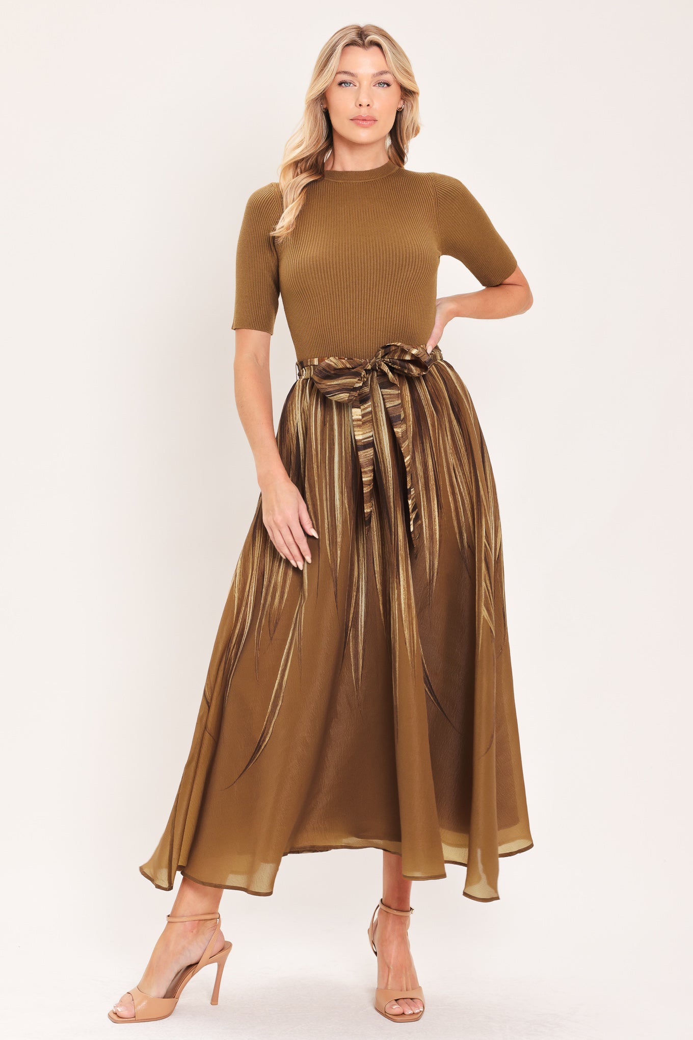 A woman modeling a brown midi dress with a short-sleeve mock neck top, pleated skirt, and a matching fabric tie belt | Flying Tomato