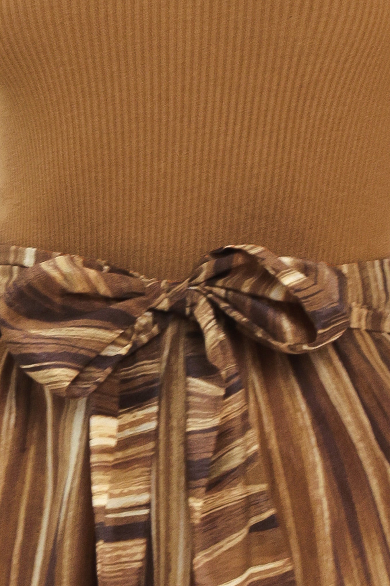A woman modeling a brown midi dress with a short-sleeve mock neck top, pleated skirt, and a matching fabric tie belt | Flying Tomato