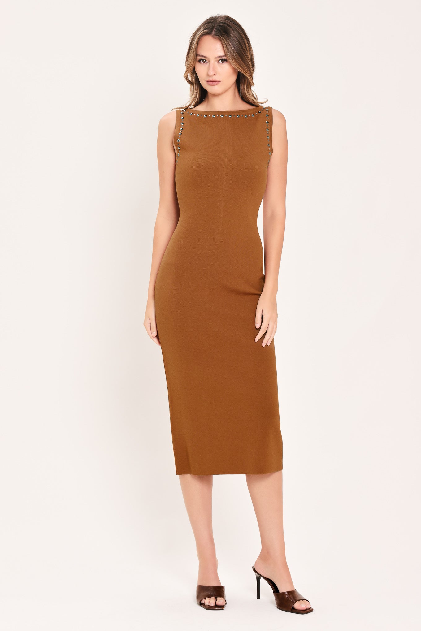 A woman wearing a sleeveless, high-neck, sweater knot bodycon midi dress in a warm camel brown color | Flying Tomato