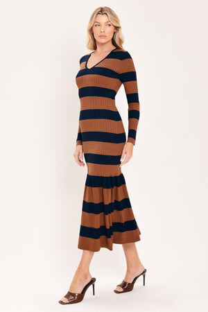 A woman modeling a long-sleeve ribbed knit midi dress with horizontal brown and navy and rust stripes, featuring a V-neckline and a flared mermaid-style hem | Flying Tomato