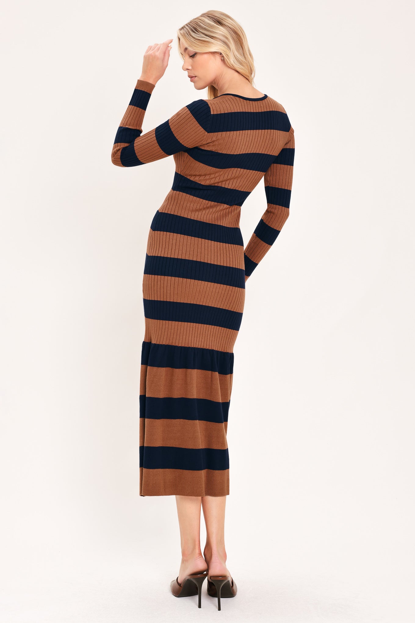 A woman modeling a long-sleeve ribbed knit midi dress with horizontal brown and navy and rust stripes, featuring a V-neckline and a flared mermaid-style hem | Flying Tomato