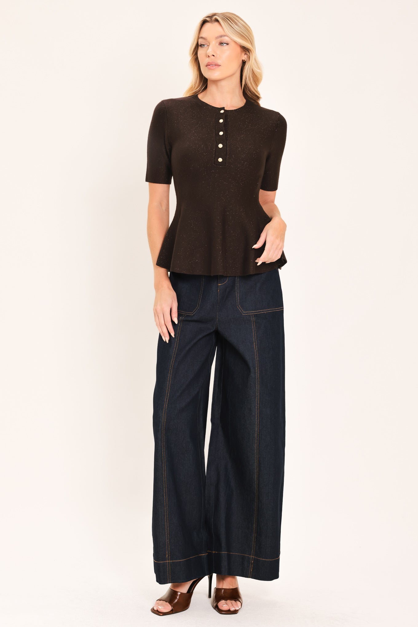 A woman modeling a short-sleeve knit top in dark brown with a buttoned henley neckline and a peplum hem | Flying Tomato