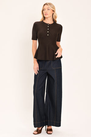 A woman modeling a short-sleeve knit top in dark brown with a buttoned henley neckline and a peplum hem | Flying Tomato