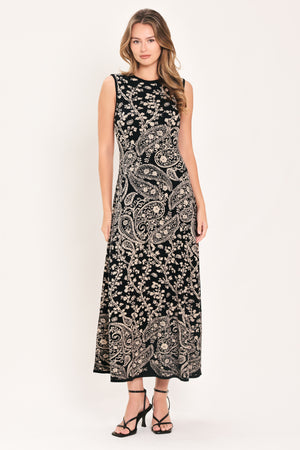 A woman wearing a sleeveless black midi dress with an intricate white paisley and floral pattern | Flying Tomato