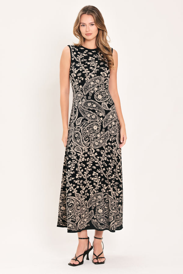 A woman wearing a sleeveless black midi dress with an intricate white paisley and floral pattern | Flying Tomato