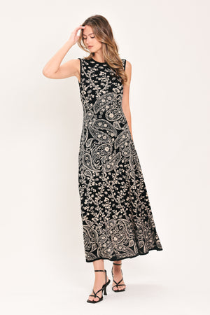 A woman wearing a sleeveless black midi dress with an intricate white paisley and floral pattern | Flying Tomato