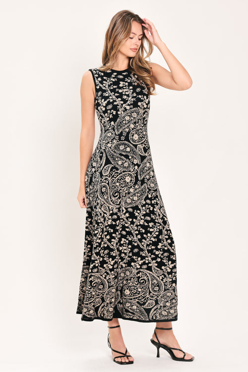 A woman wearing a sleeveless black midi dress with an intricate white paisley and floral pattern | Flying Tomato