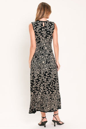 A woman wearing a sleeveless black midi dress with an intricate white paisley and floral pattern | Flying Tomato