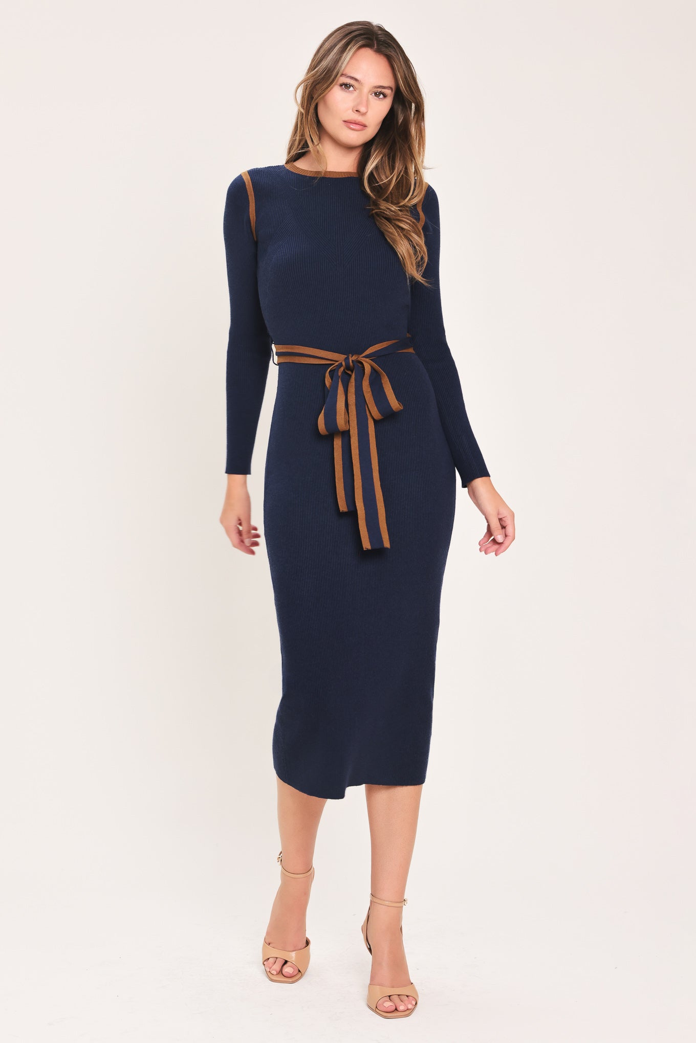 A woman modeling a navy blue long-sleeve midi dress with brown trim details on the shoulders and a matching brown tie belt at the waist | Flying Tomato