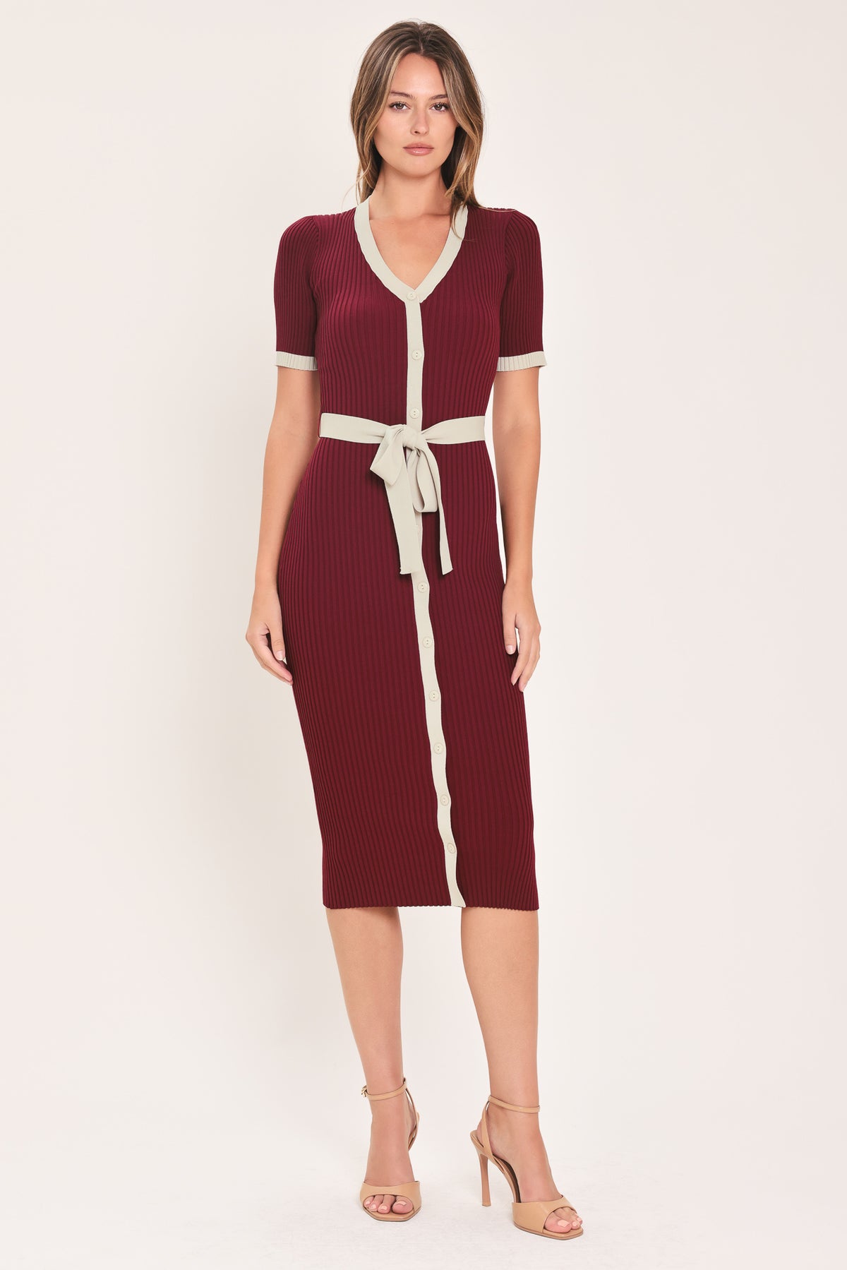 A woman models a short-sleeve ribbed knit midi dress in deep burgundy with cream trim details, including the collar, front placket, and matching tie belt | Flying Tomato