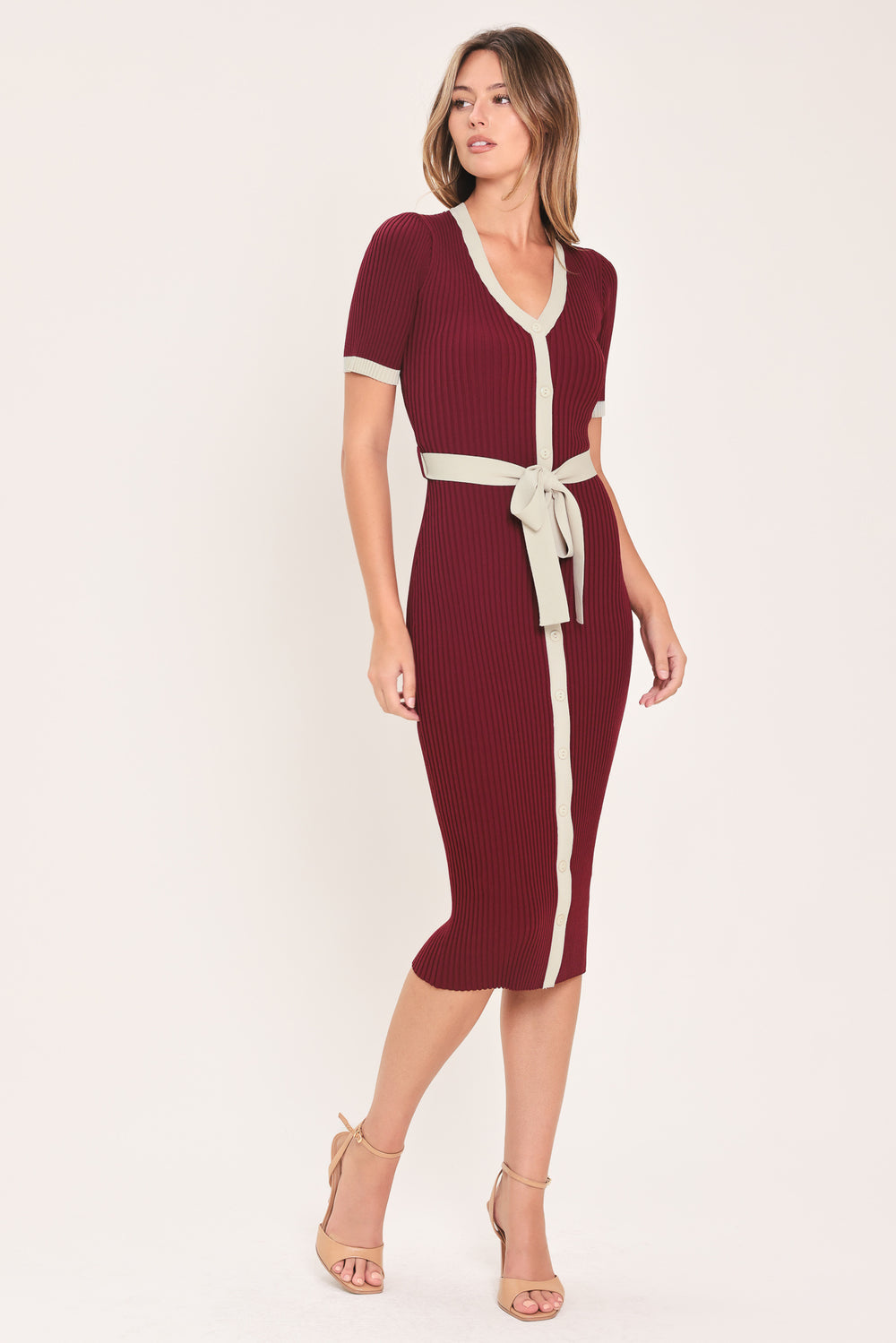 A woman models a short-sleeve ribbed knit midi dress in deep burgundy with cream trim details, including the collar, front placket, and matching tie belt | Flying Tomato