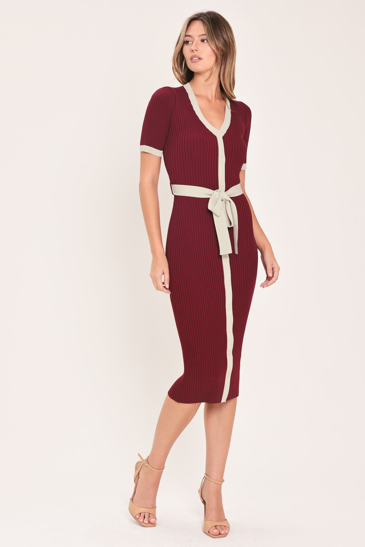 A woman models a short-sleeve ribbed knit midi dress in deep burgundy with cream trim details, including the collar, front placket, and matching tie belt | Flying Tomato