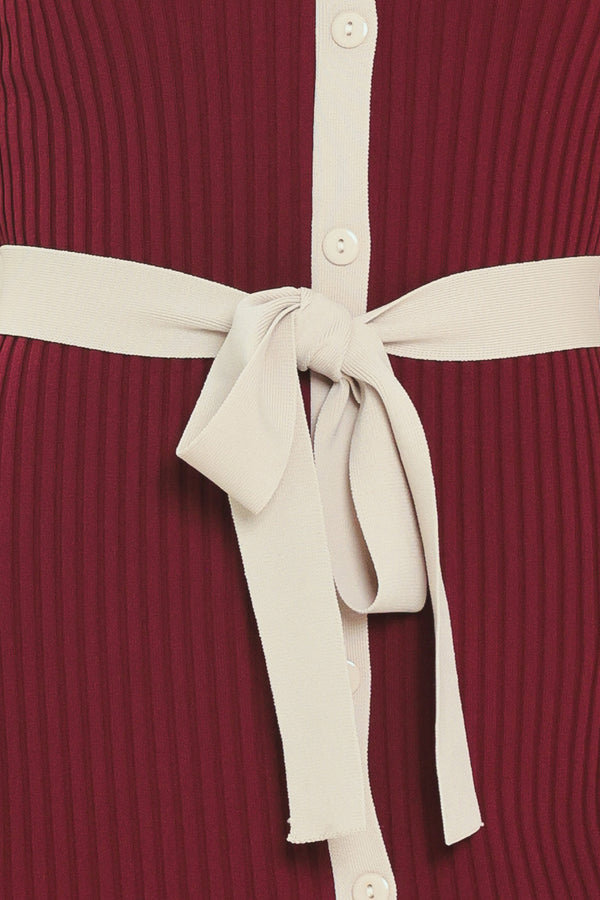A woman models a short-sleeve ribbed knit midi dress in deep burgundy with cream trim details, including the collar, front placket, and matching tie belt | Flying Tomato