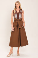 A woman wearing a sleeveless midi dress with brown and white striped top and solid brown skirt featuring a matching tie belt | Flying Tomato