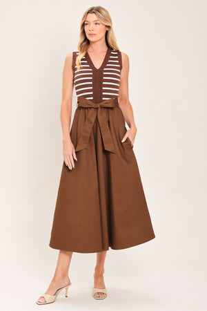 A woman wearing a sleeveless midi dress with brown and white striped top and solid brown skirt featuring a matching tie belt | Flying Tomato