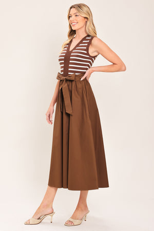 A woman wearing a sleeveless midi dress with brown and white striped top and solid brown skirt featuring a matching tie belt | Flying Tomato