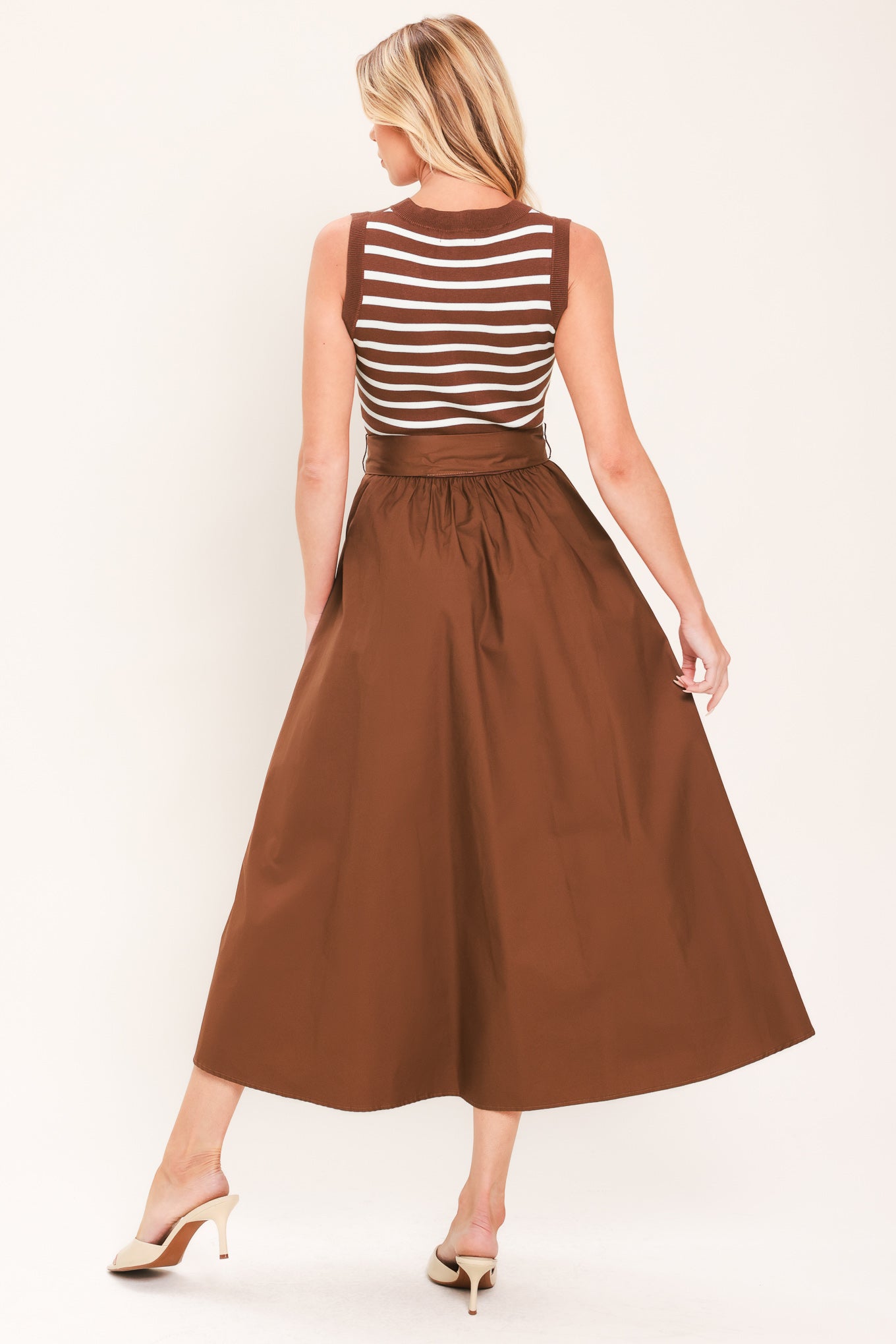 A woman wearing a sleeveless midi dress with brown and white striped top and solid brown skirt featuring a matching tie belt | Flying Tomato