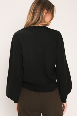 A woman modeling a black crewneck sweatshirt featuring a large embroidered floral design in purple, green, and gold on the front | Flying Tomato