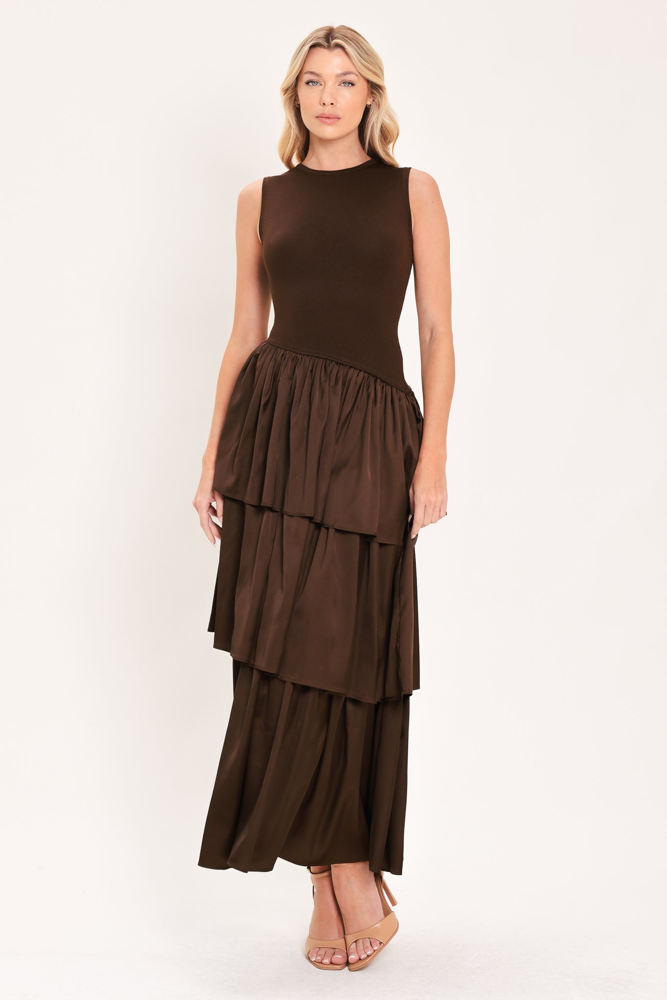 A woman modeling a sleeveless, high-neck, tiered skirt maxi dress in a deep chocolate brown color with an asymmetrical drop waist | Flying Tomato
