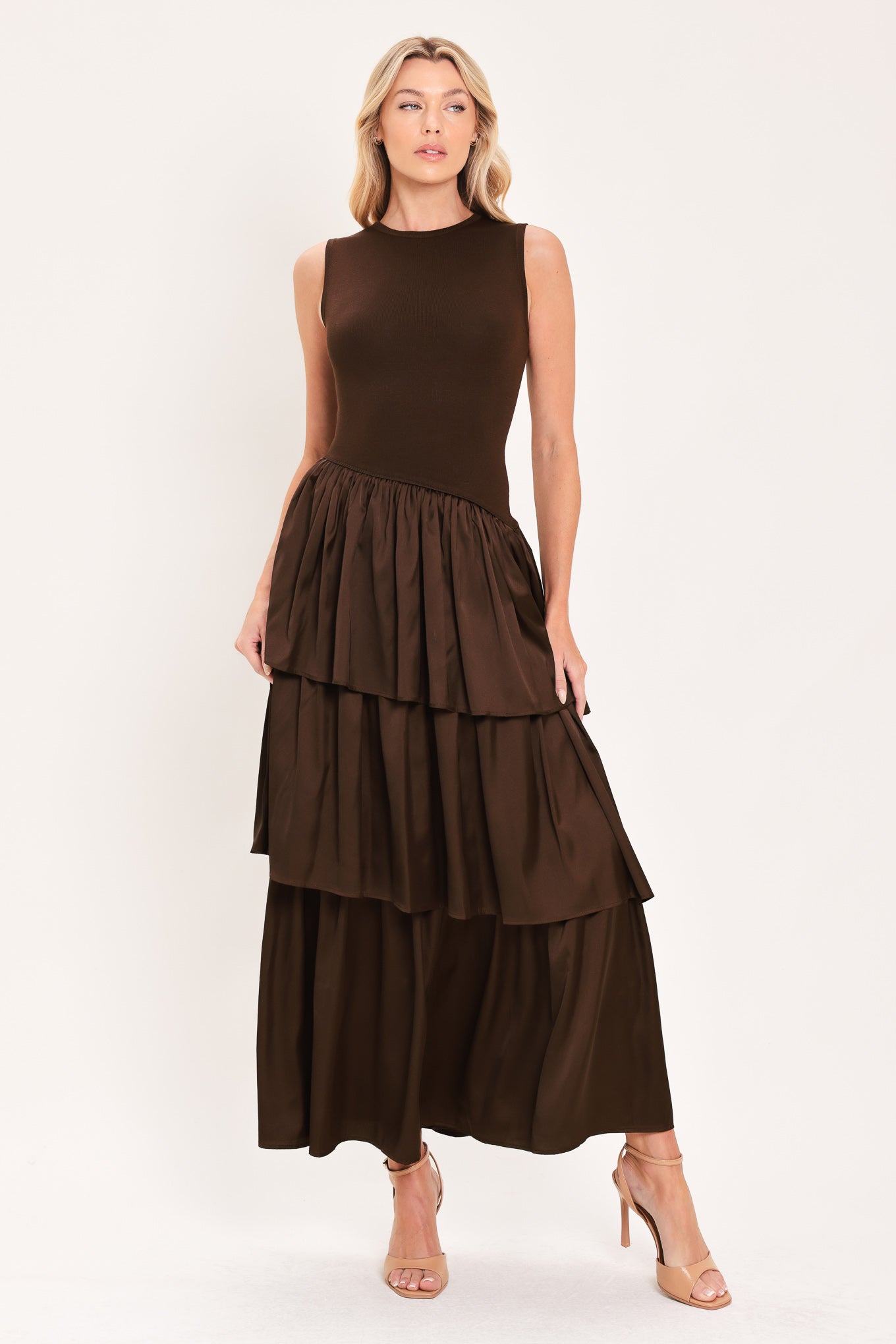 A woman modeling a sleeveless, high-neck, tiered skirt maxi dress in a deep chocolate brown color with an asymmetrical drop waist | Flying Tomato