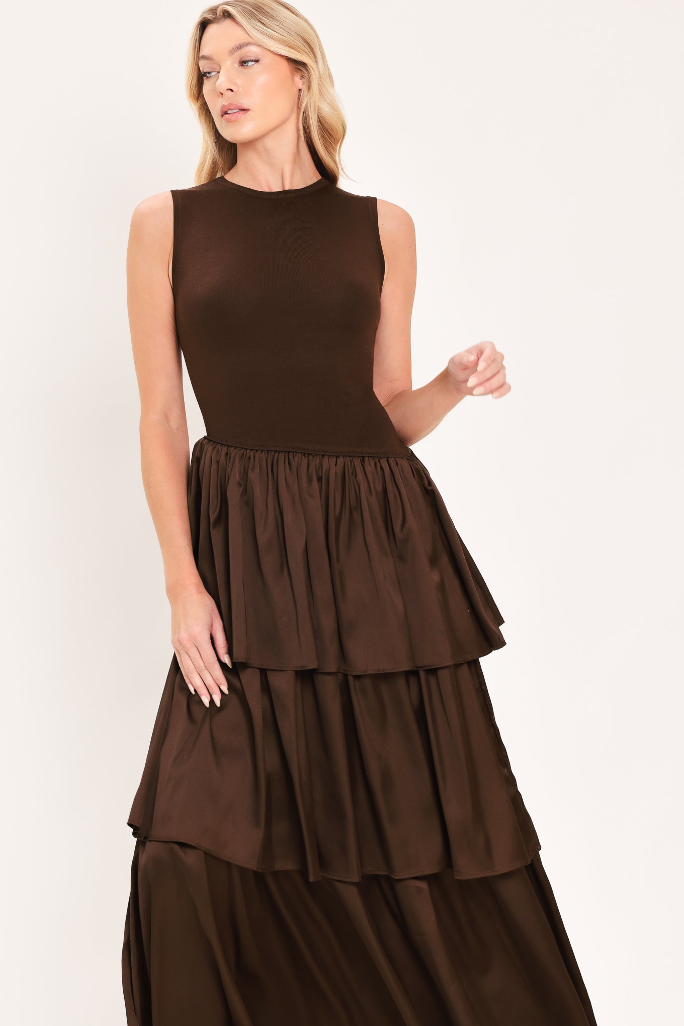 A woman modeling a sleeveless, high-neck, tiered skirt maxi dress in a deep chocolate brown color with an asymmetrical drop waist | Flying Tomato