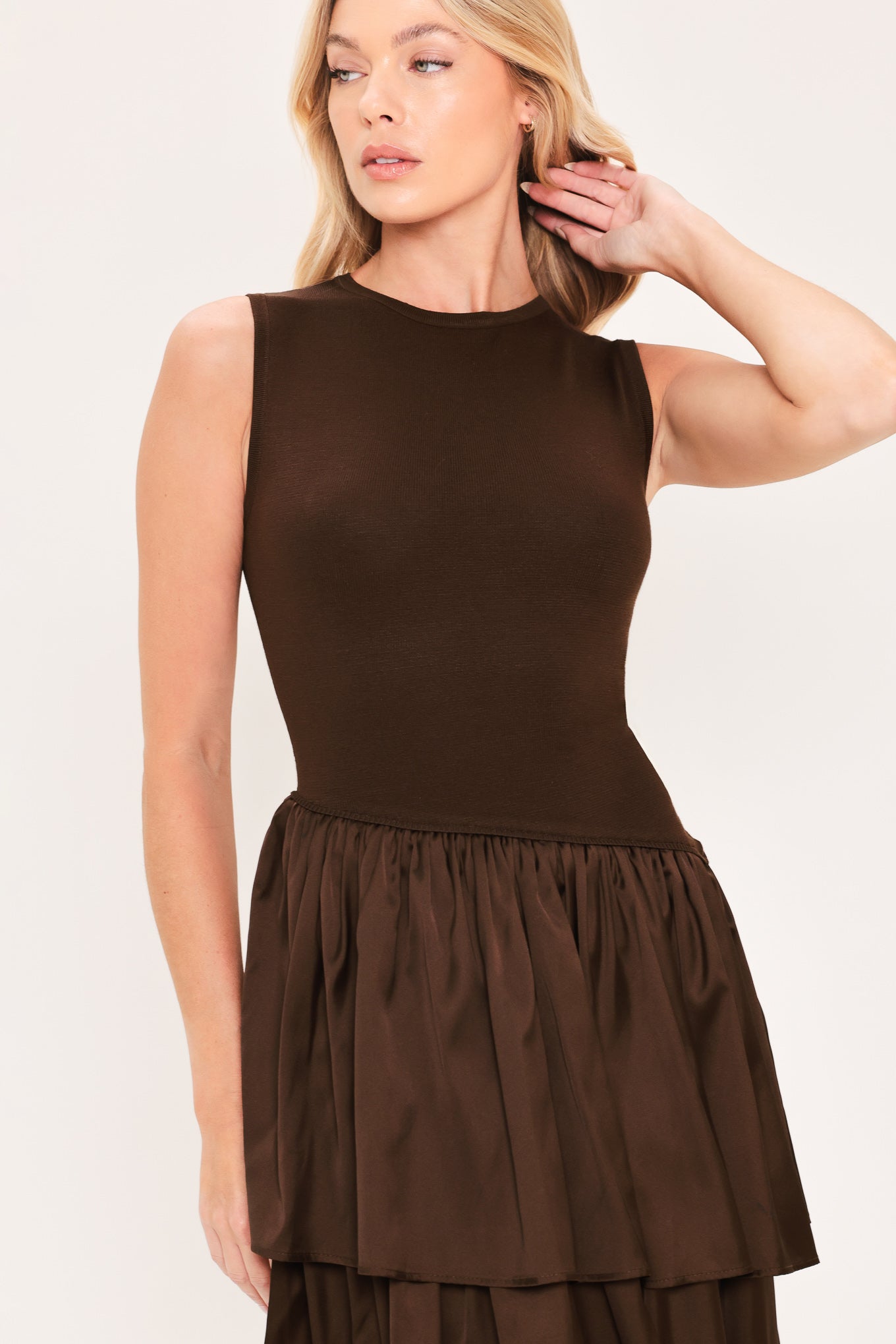 A woman modeling a sleeveless, high-neck, tiered skirt maxi dress in a deep chocolate brown color with an asymmetrical drop waist | Flying Tomato