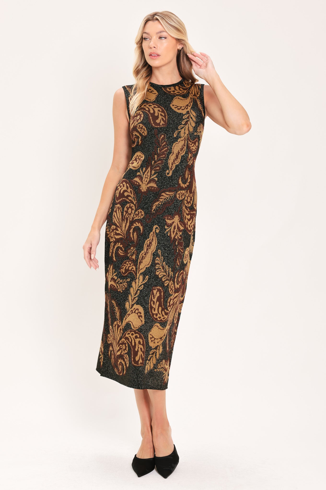 A woman modeling a sleeveless midi dress with a black base and an intricate gold metallic botanical and scroll pattern | Flying Tomato