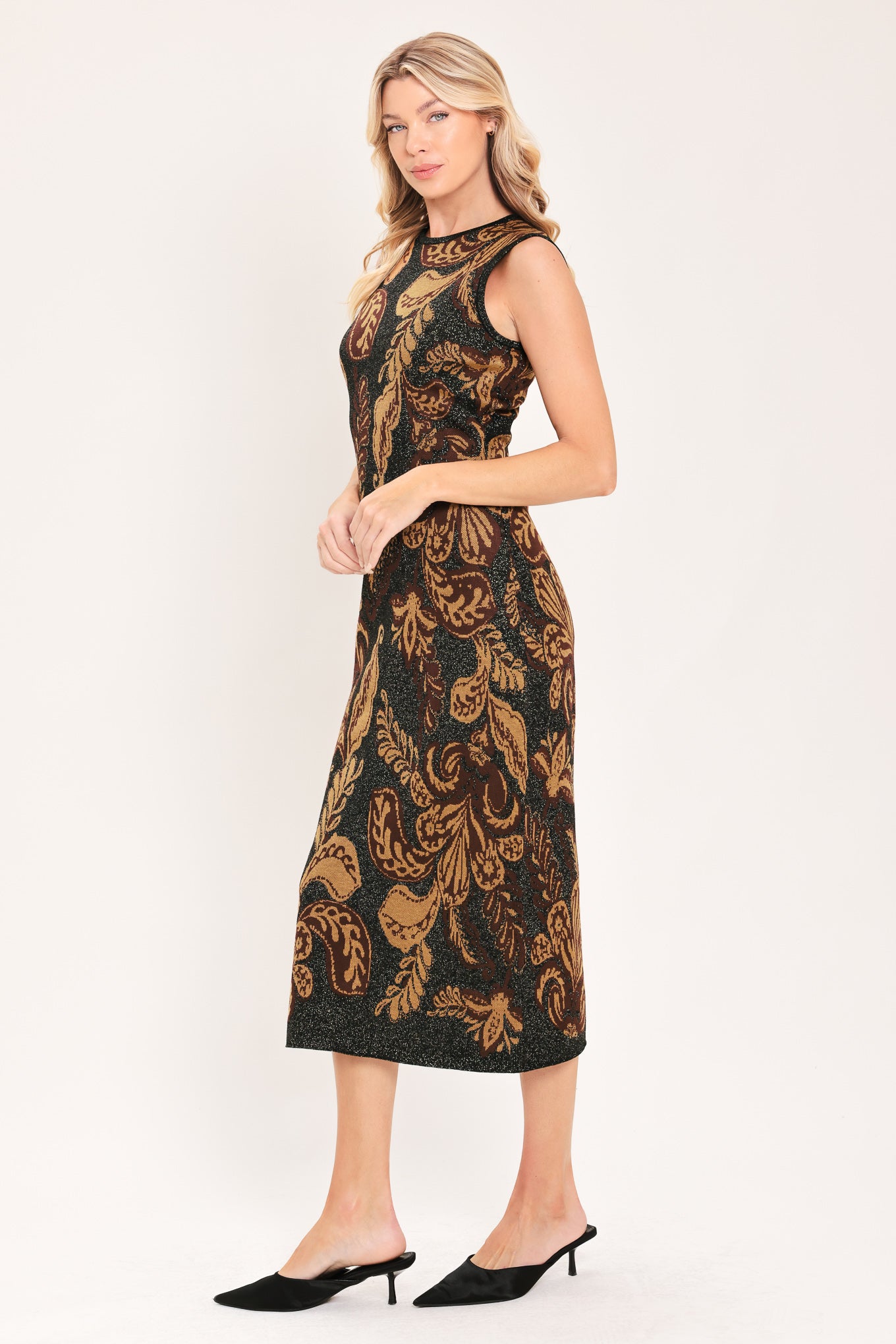 A woman modeling a sleeveless midi dress with a black base and an intricate gold metallic botanical and scroll pattern | Flying Tomato
