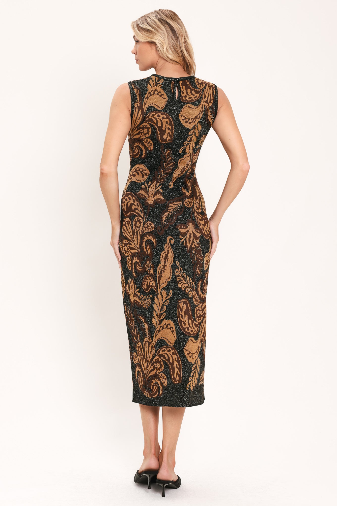 A woman modeling a sleeveless midi dress with a black base and an intricate gold metallic botanical and scroll pattern | Flying Tomato