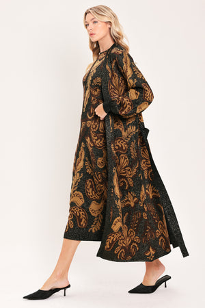 A woman modeling a sleeveless midi dress with a black base and an intricate gold metallic botanical and scroll pattern | Flying Tomato