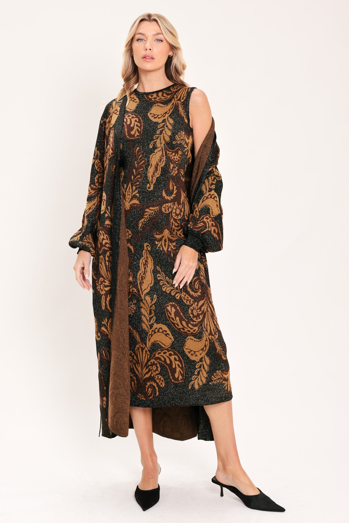 A woman modeling a sleeveless midi dress with a black base and an intricate gold metallic botanical and scroll pattern | Flying Tomato