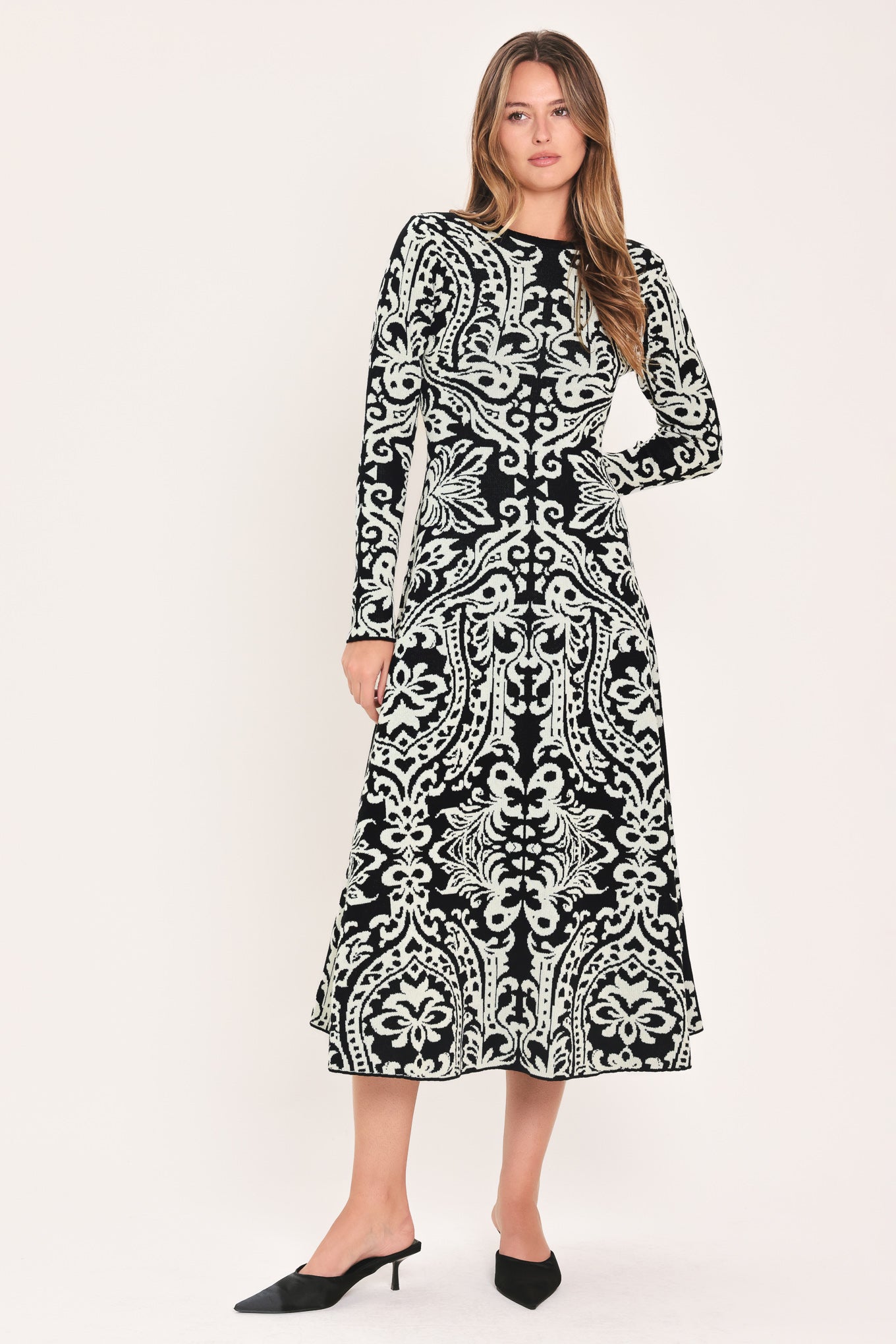 A woman modeling a long-sleeve midi dress with an intricate black and white damask pattern | Flying Tomato
